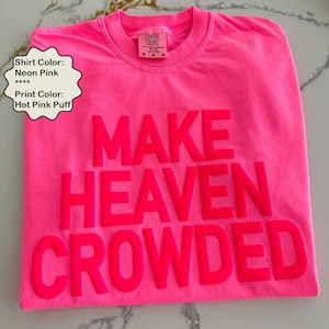 May include: Neon pink t-shirt with the text "MAKE HEAVEN CROWDED" printed in hot pink puff lettering.