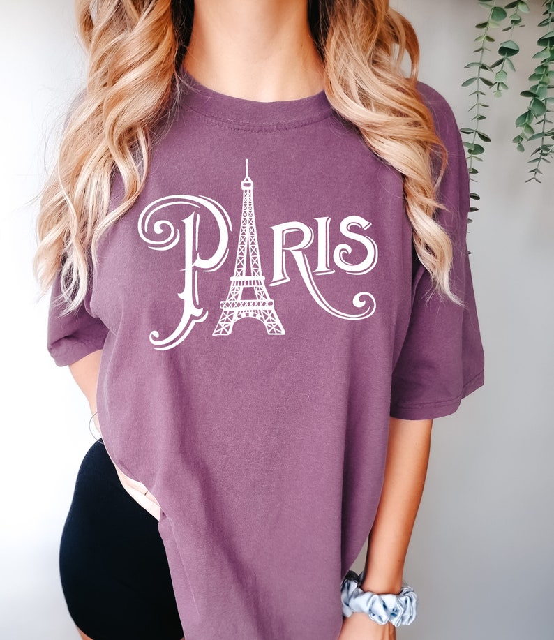 May include: A purple t-shirt with a white graphic of the Eiffel Tower and the word "PARIS" in a stylized font.