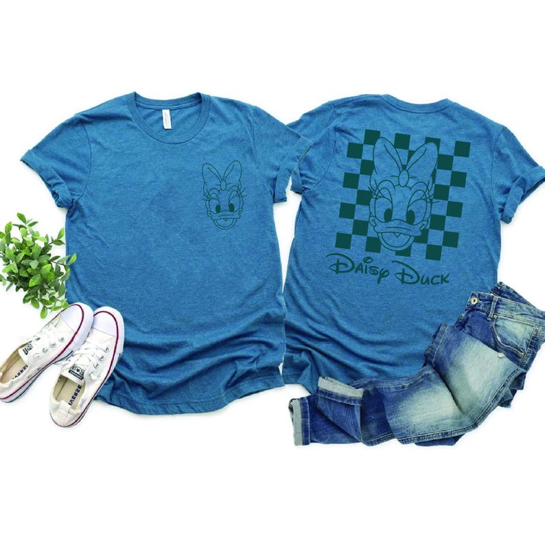 Pu&ograve; includere: Due magliette blu con un contorno verde di Daisy Duck. Una maglietta ha un motivo a scacchi e il testo "Daisy Duck". L'altra maglietta ha un'immagine pi&ugrave; piccola di Daisy Duck.