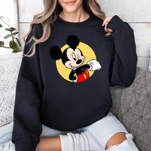 May include: Black sweatshirt with a yellow circle and a cartoon image of Mickey Mouse in a red and black outfit. Mickey Mouse is winking and giving a thumbs up.