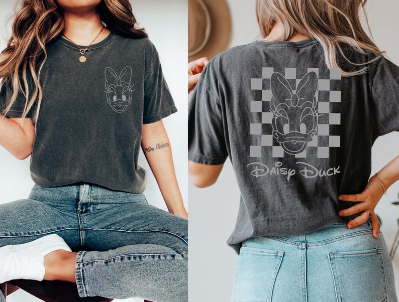 K&ouml;nnte beinhalten: Ein dunkelgraues T-Shirt mit einem wei&szlig;en Umriss von Daisy Duck auf der Vorderseite und einem wei&szlig;en Umriss von Daisy Duck auf einem karierten Hintergrund auf der R&uuml;ckseite mit dem Text "Daisy Duck" darunter.