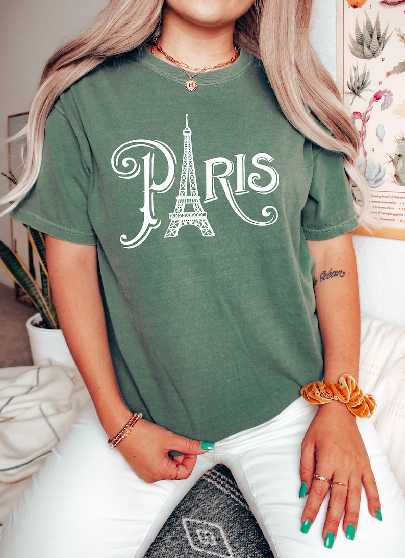May include: A green t-shirt with a white graphic of the Eiffel Tower and the word "PARIS" in a stylized font.