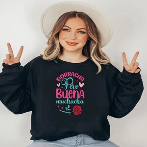 May include: Black sweatshirt with a pink and teal graphic that says "Borracha Pero Buena Muchacha" with a red rose and hearts.
