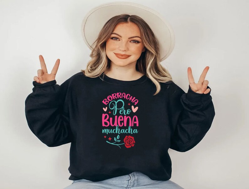 May include: Black sweatshirt with a pink and teal graphic that says "Borracha Pero Buena Muchacha" with a red rose and hearts.