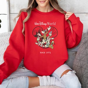 Puede incluir: Sudadera roja con un gr&aacute;fico blanco de Mickey Mouse y sus amigos frente a un espect&aacute;culo de fuegos artificiales. El texto "Walt Disney World" y "Since 1971" est&aacute;n impresos en la sudadera.