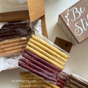 K&ouml;nnte beinhalten: Sortiment von Fruchtlederr&ouml;llchen in verschiedenen Farben, darunter Rot, Gelb und Braun, verpackt in durchsichtigen Plastikt&uuml;ten. Die T&uuml;ten sind mit dem Text "ecofruits_ua" beschriftet.