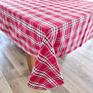 May include: Red and white checked tablecloth with a brown and white checked pattern. The tablecloth is laid out on a wooden table.
