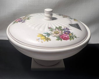 May include: White ceramic covered bowl with a floral design. The bowl has a pedestal base and a knob on the lid.