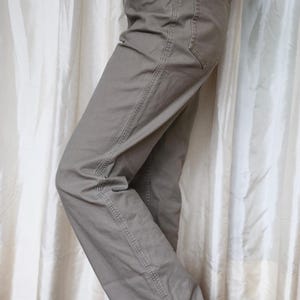 May include: A pair of light brown straight-leg trousers with a single back pocket.