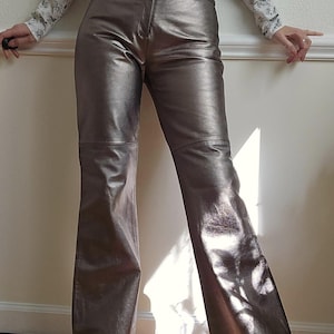 May include: A pair of silver metallic leather pants with a wide leg silhouette.