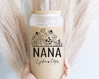 May include: A clear glass tumbler with a bamboo lid and a black straw. The tumbler has a floral design and the text "NANA Lydia Peter" printed on it.