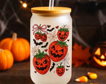 May include: A frosted glass tumbler with a bamboo lid and a clear straw. The tumbler is decorated with orange jack-o'-lanterns, bats, and spiderwebs. The background includes pumpkins and candy corn.