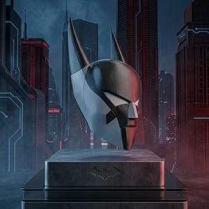 K&ouml;nnte beinhalten: Ein schwarz-silberner Batman Beyond Helm mit spitzen Ohren und einer stilisierten Gesichtsmaske, montiert auf einem rechteckigen Sockel mit Fledermaus-Emblem. Der Sockel tr&auml;gt unten mittig den Schriftzug BATMAN BEYOND HELMET.