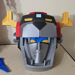 以下が含まれることがあります： ボルtronのライオンの頭部の3Dプリントモデル。ボルtronアニメシリーズのロボットです。モデルはシルバー、ブラック、レッド、イエロー、ブルーでペイントされています。