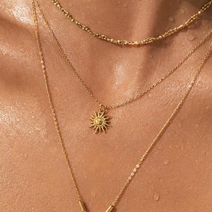 Peut inclure: Un ensemble de trois colliers superposés en or. La chaîne supérieure est de style torsadé texturé. La chaîne intermédiaire présente un petit pendentif soleil. La plus longue chaîne comporte un anneau avec une étoile et un pendentif soleil.