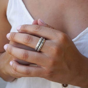 Puede incluir: Dos anillos de plata con acabado texturizado, usados en un dedo.