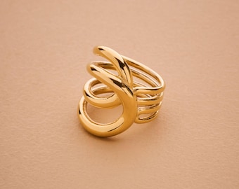 May include: A gold-colored ring with a unique, swirling design. The ring features multiple bands that curve and overlap, creating an eye-catching, sculptural look. The ring is made of a shiny, reflective metal.