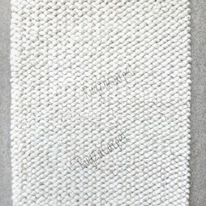 Puede incluir: Alfombra blanca y esponjosa hecha de bucles tejidos apretados. La alfombra tiene una textura sutil y una sensaci&oacute;n suave y mullida.
