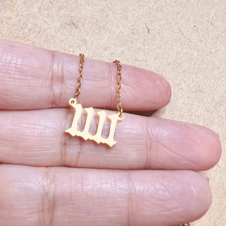 May include: A gold chain necklace with a Roman numeral 'III' pendant. The pendant is made of metal and has a shiny finish.