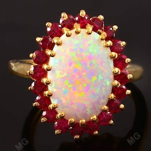 May include: A gold ring with a large white opal surrounded by a halo of red rubies.