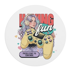 May include: Round white gaming mousepad featuring a cartoon illustration of a woman with purple hair and headphones holding a yellow game controller. Text includes "HAVING fun" and "PRESS START TO CONTINUE".
