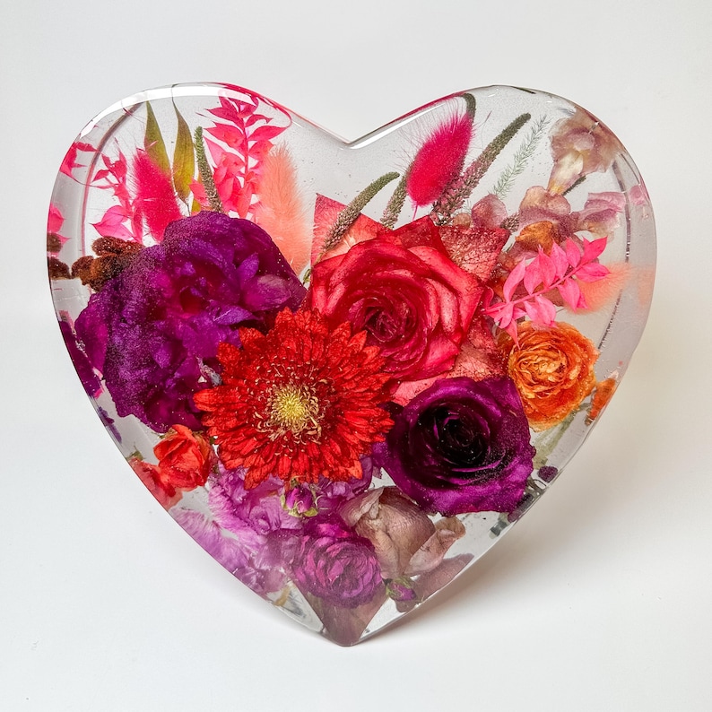 May include: A heart-shaped resin sculpture filled with a variety of preserved flowers in shades of pink, red, purple, and orange.