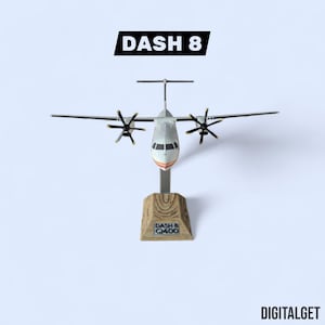May include: A model airplane of a Dash 8 Q400, with a silver fuselage, black propellers, and a wooden base. The text "DASH 8" is above the plane, and "DIGITALGET" is below. The model is displayed against a light blue background.
