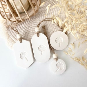 Peut inclure: Quatre ornements en céramique blanche avec un motif de pissenlit. Les ornements sont suspendus à une ficelle et ont une esthétique rustique et champêtre.