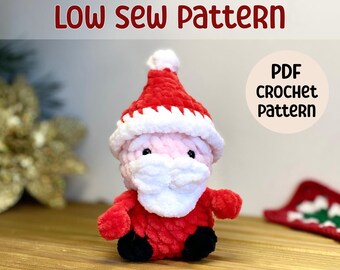 May include: A crocheted Santa Claus amigurumi toy with a red hat, white beard, and black eyes. The toy is sitting on a wooden surface. The text "LOW SEW PATTERN" is at the top of the image. The text "PDF CROCHET PATTERN" is in a circle at the top right of the image.