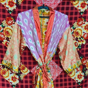 May include: A colorful silk robe with a floral pattern. The robe has a long, flowing design and is tied at the waist with a sash.
