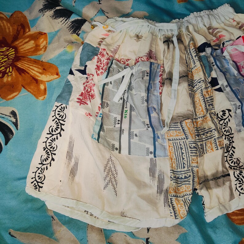 May include: A white patchwork skirt with a variety of colorful patterns, including floral, geometric, and striped designs. The skirt has a drawstring waist and a relaxed fit.