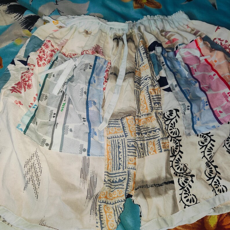 May include: A patchwork skirt made from different fabrics with a variety of patterns and colors, including white, blue, pink, and black.