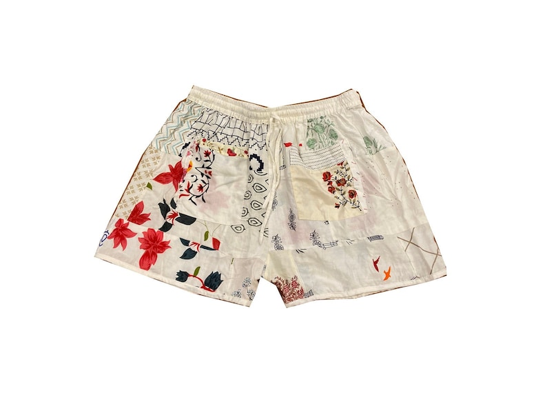 May include: White cotton shorts with a patchwork design featuring floral and geometric patterns in shades of red, blue, and green.