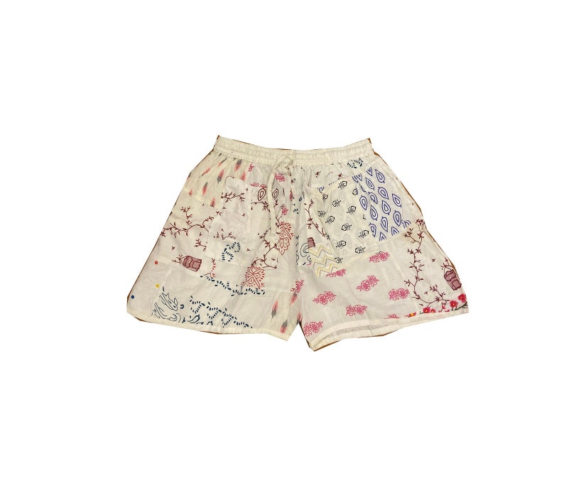 May include: White cotton shorts with a patchwork design featuring various floral and geometric patterns in shades of pink, blue, and black.