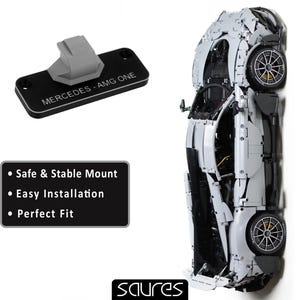 May include: A black plastic mount with the text "MERCEDES-AMG ONE" printed on it. The mount is designed to hold a model car. The text "Safe & Stable Mount", "Easy Installation", and "Perfect Fit" are printed on a black rectangle below the mount.