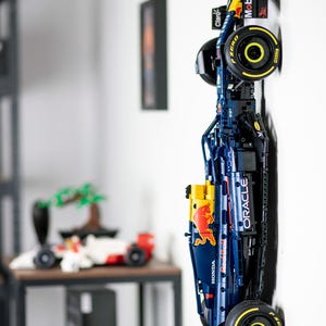 Puede incluir: Un modelo Lego azul y rojo de un coche de carreras de F&oacute;rmula 1 con los logotipos de Oracle y Red Bull. El coche est&aacute; montado en una pared con las ruedas hacia afuera.