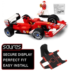 May include: A red and white Ferrari F2004 race car model with black tires and a small figurine. The image also includes a black display stand and a sign that says "SECURE DISPLAY, PERFECT FIT, EASY INSTALL."