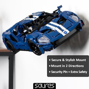 Peut inclure: Un modèle Lego bleu et blanc d'une voiture de course Ford GT. La voiture est suspendue en l'air et semble flotter. Le texte sur l'image indique : "Montage sécurisé et élégant", "Montage dans 2 directions" et "Goupille de sécurité = Sécurité supplémentaire".