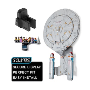 May include: A light gray plastic wall mount bracket for a model starship, featuring a black rectangular display stand with a row of small character figurines and a black sign with the text SAURES SECURE DISPLAY PERFECT FIT EASY INSTALL.