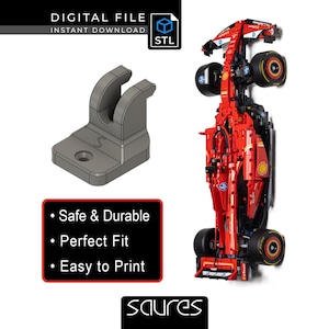 Puede incluir: Un soporte gris impreso en 3D y un modelo de coche de carreras rojo se muestran sobre un fondo blanco. El soporte tiene una parte superior curva y una base con un agujero. El texto en una caja roja dice "Safe & Durable", "Perfect Fit" y "Easy to Print".
