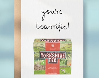 Può includere: Un biglietto d'auguri bianco con busta marrone che presenta un'illustrazione disegnata a mano di una scatola di tè Yorkshire. Il testo sopra la scatola recita you're tea-rrific! L'illustrazione include colline verdi, una pecora e 250g.
