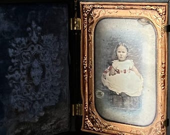 Original 1850s daguerreotype of a young girl in ornate gutta percha case. Rare Victorian photo with deep historical and decorative appeal.