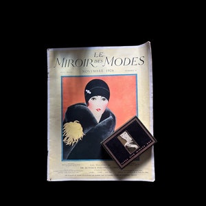 May include: A vintage magazine cover featuring a woman in a black hat and fur coat. The magazine is titled "Le Miroir des Modes" and the date is November 1926. A small box with the text "Lotus Five Minutes Set" is on top of the magazine.
