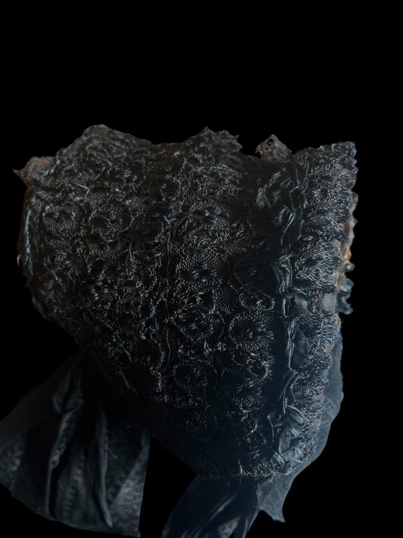 Puede incluir: Un gorro de encaje negro con un borde rizado. El gorro est&aacute; hecho de encaje delicado e intrincado y tiene un drapeado suave y fluido.
