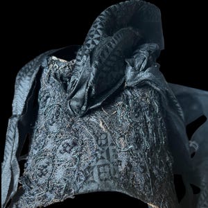 Puede incluir: Un sombrero de tela negro con un patr&oacute;n geom&eacute;trico. El sombrero est&aacute; hecho de un material suave y texturizado y tiene un borde deshilachado.