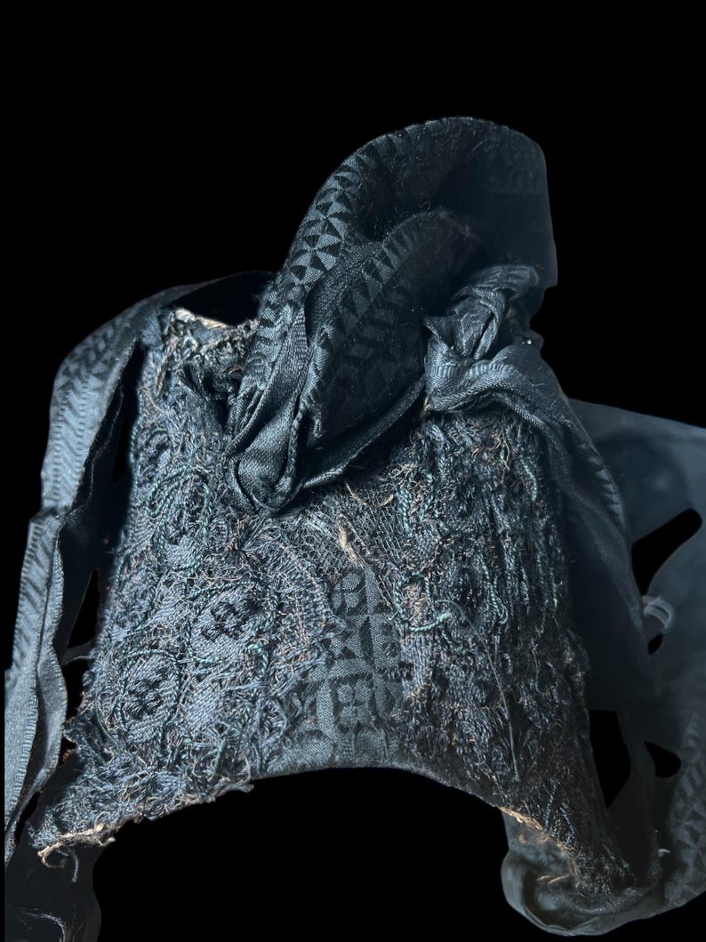 Puede incluir: Un sombrero de tela negro con un patr&oacute;n geom&eacute;trico. El sombrero est&aacute; hecho de un material suave y texturizado y tiene un borde deshilachado.