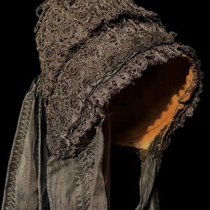Puede incluir: Un gorro de encaje negro con una cinta larga negra atada en la parte posterior. El gorro est&aacute; hecho de encaje delicado y tiene un borde con volantes.