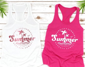 May include: Two racerback tank tops, one white and one fuchsia. Each top features a circular design with the word "Summer" and the phrases "Sunrise, Sunburn, Repeat, Sunset" around a palm tree and waves.