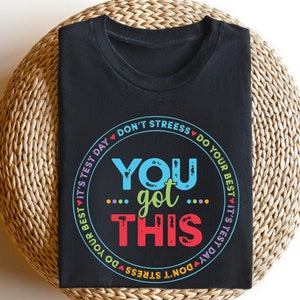 May include: Black t-shirt with a colorful circle graphic that says "You got this" and "Don't stress, do your best, it's test day".