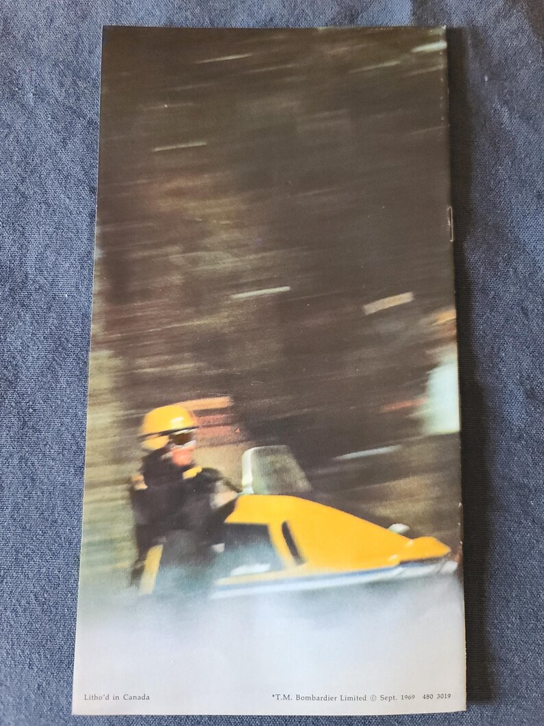 May include: Vintage advertisement featuring a yellow snowmobile in motion. The driver wears a yellow helmet and dark clothing. The background is blurred, suggesting speed. Text at the bottom reads "Litho'd in Canada" and "T.M. Bombardier Limited &copy; Sept. 1969 480 3019."